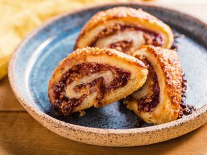 Three almond-raspberry rugelach on a ceramic plate. 