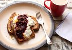French toast topped with blackberry compote and ricotta next to a mug of coffee. 