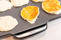 A closeup of pancakes cooking on an electric griddle