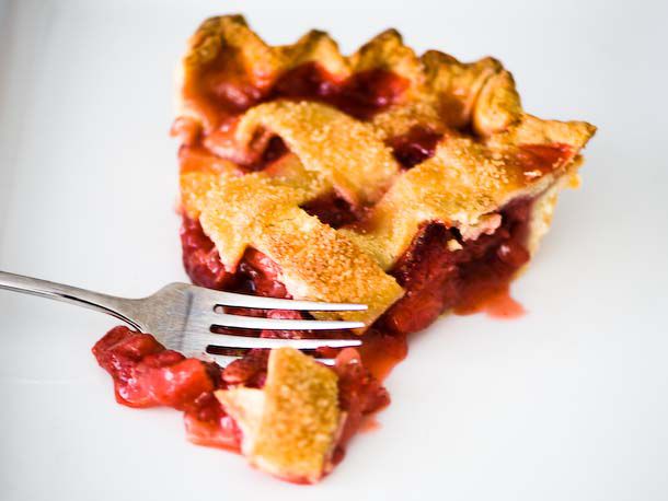 A close up of a slice of strawberry pie with a lattice top.