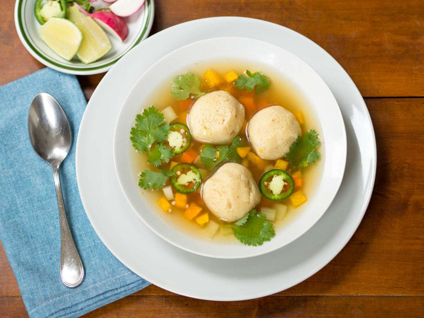 A white bowl filled with masa-ball soup and garnished with cilantro.