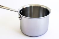 A pot from the All-Clad D3 3-Ply Stainless Steel Cookware Set 10 Piece on a white surface