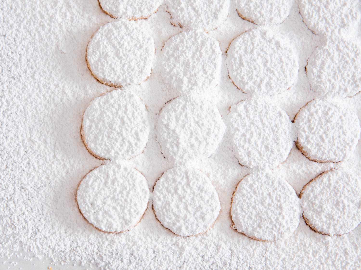 Rows of lemon meltaway cookies covered in a heavy layer of powdered sugar