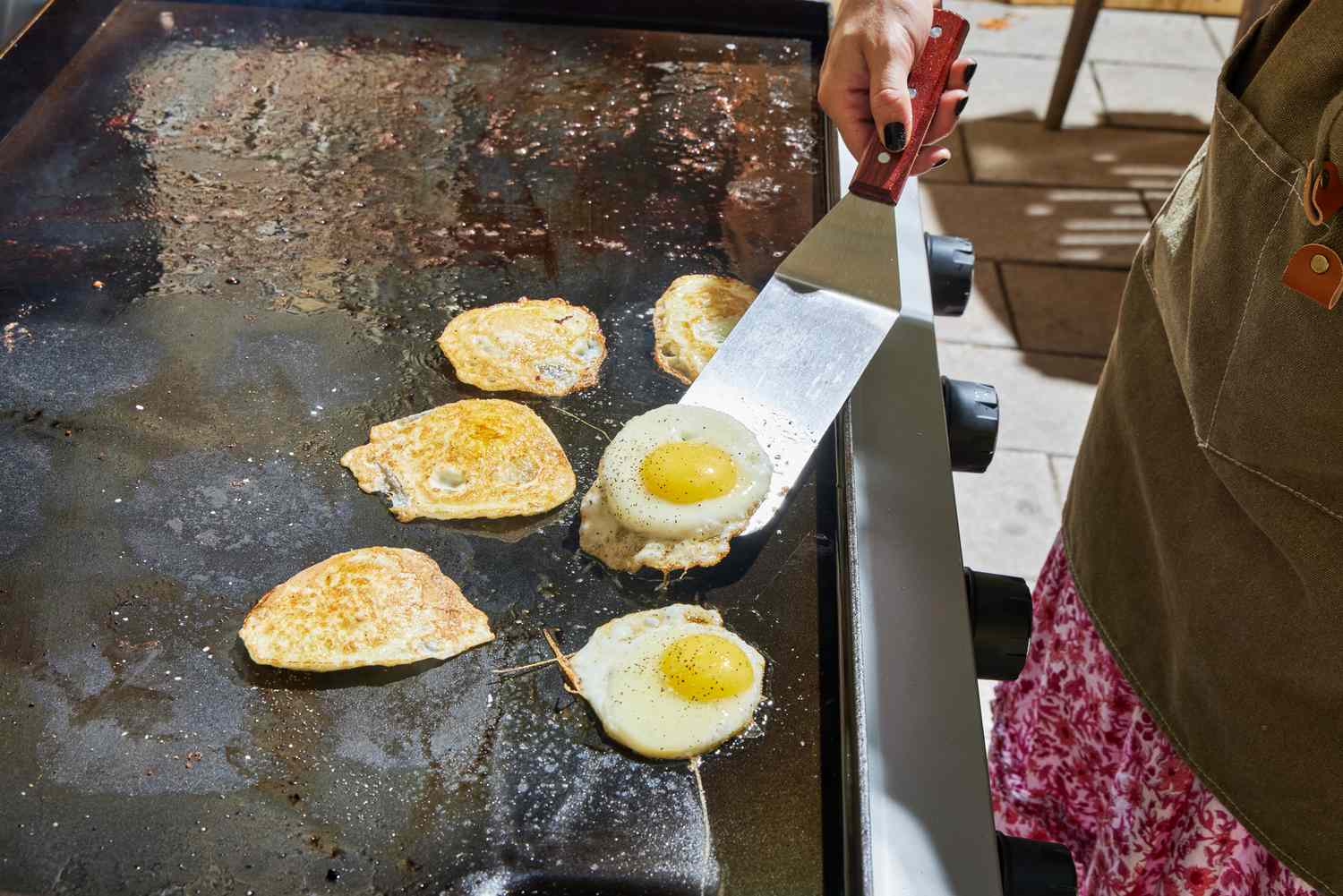 A person cooks eggs on the Weber 36 Inch Gas Griddle