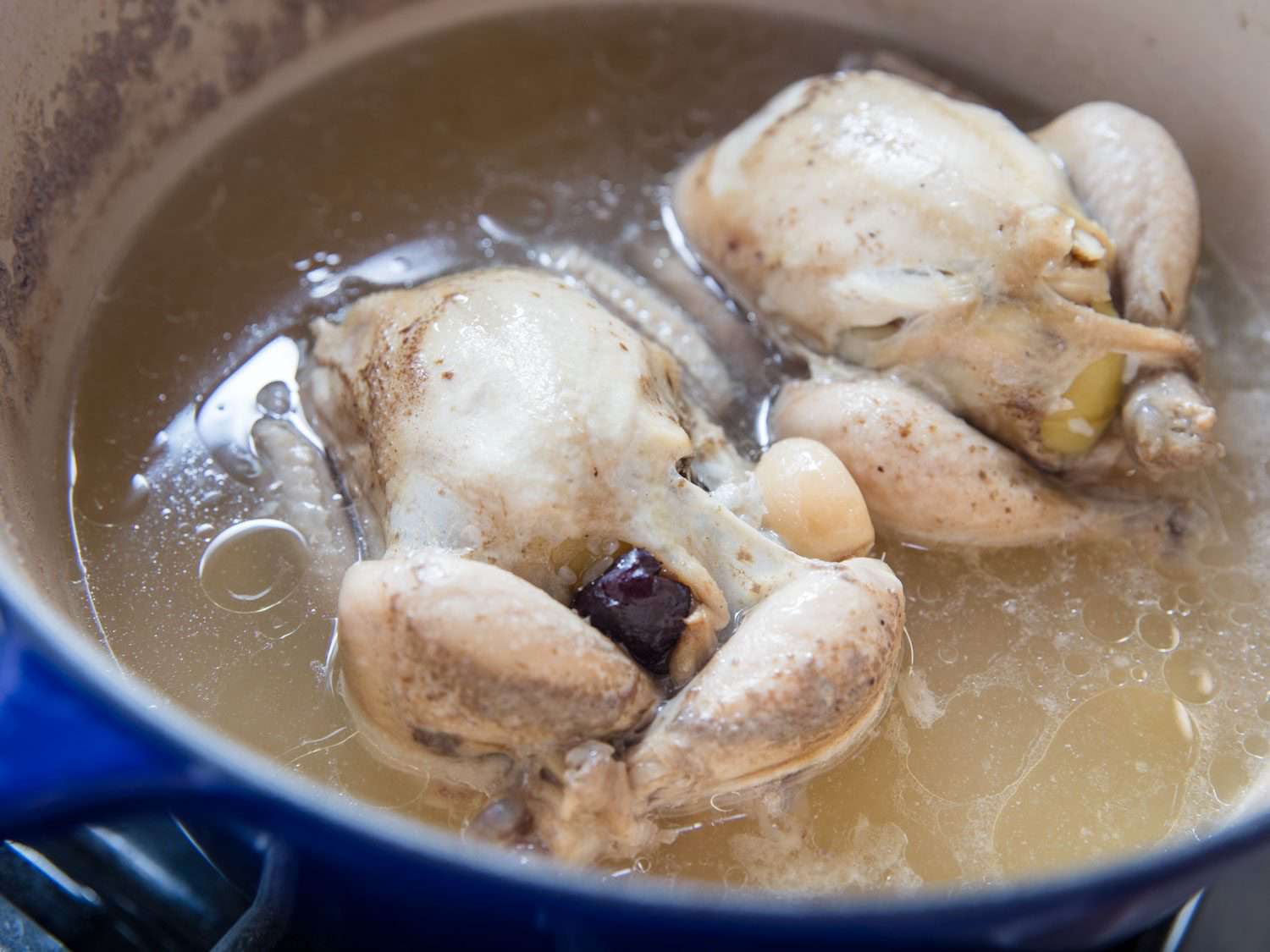 Stuffed chickens and broth in the cooking pot for Korean samgyetang.