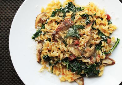 Overhead shot of a plate of pasta tossed with pancetta, mushrooms, and wilted greens