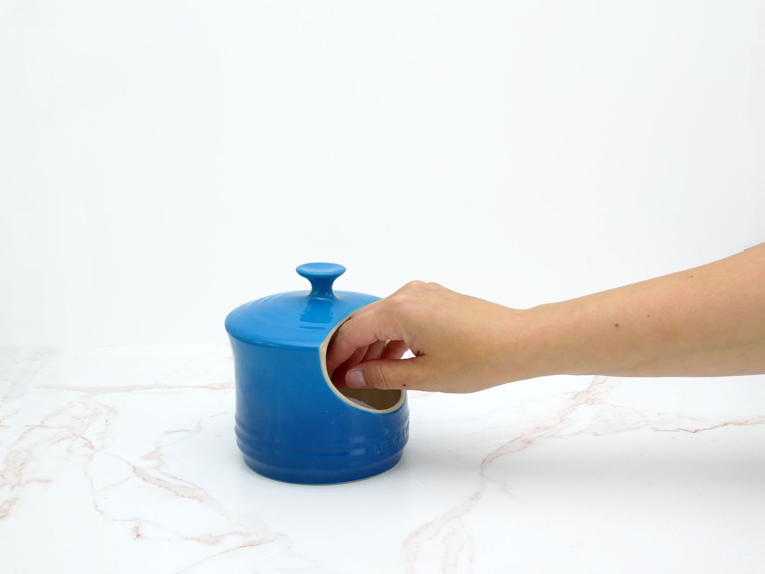 a hand reaching inside the le creuset salt cellar