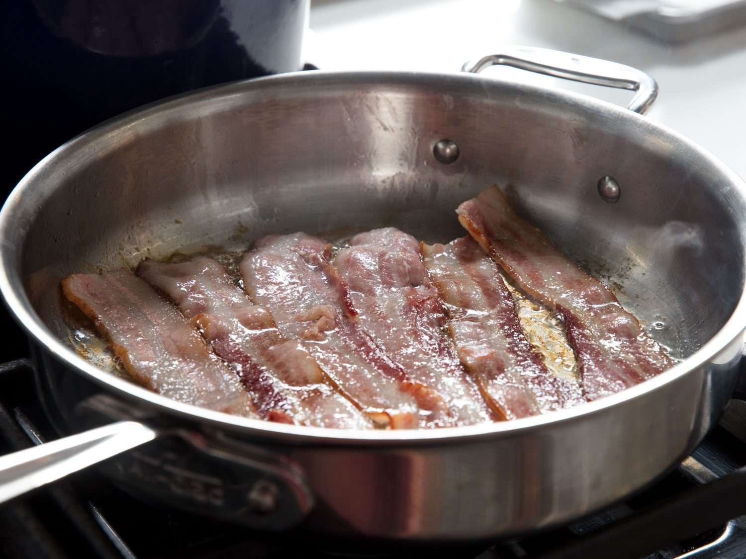 Cooking bacon slices in a skillet.