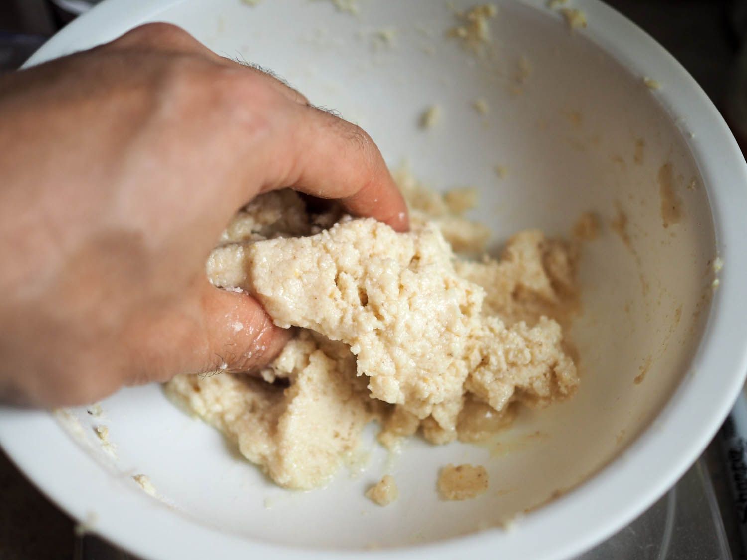 Author mixing masa dough in a bowl by hand.