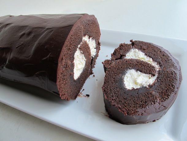 A chocolate roll with a slice cut out on a serving plate. 