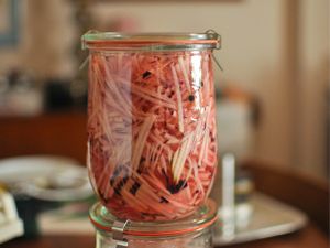 Two stacked Weck canning jars filled with shredded kohlrabi quick pickle.