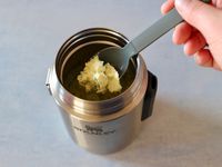 a person taking a scoop of egg salad out of the stanley all in one food jar. 