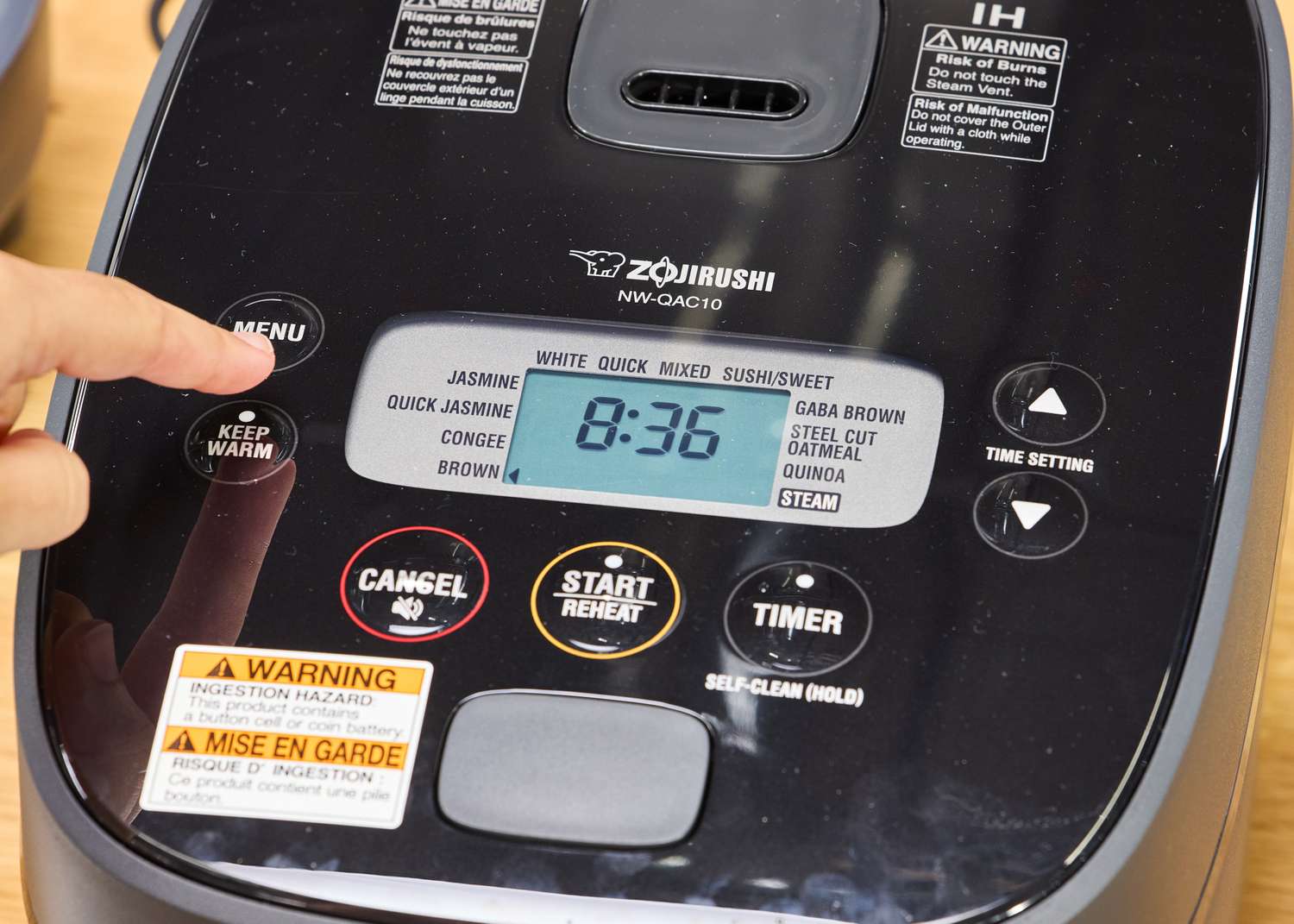 A person presses the button on the top of the Zojirushi NW-QAC10 Induction Heating Rice Cooker & Warmer