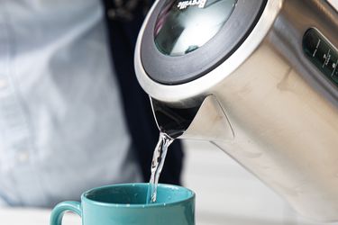 A closeup look at the Breville tea kettle pouring water into a light blue mug