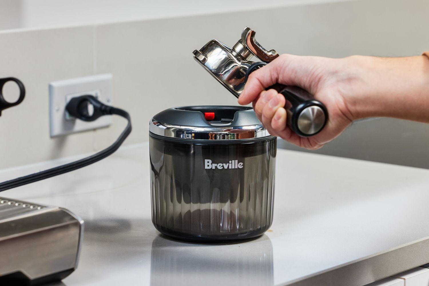 A person removing an empty portafilter from the Breville Puck Sucker.