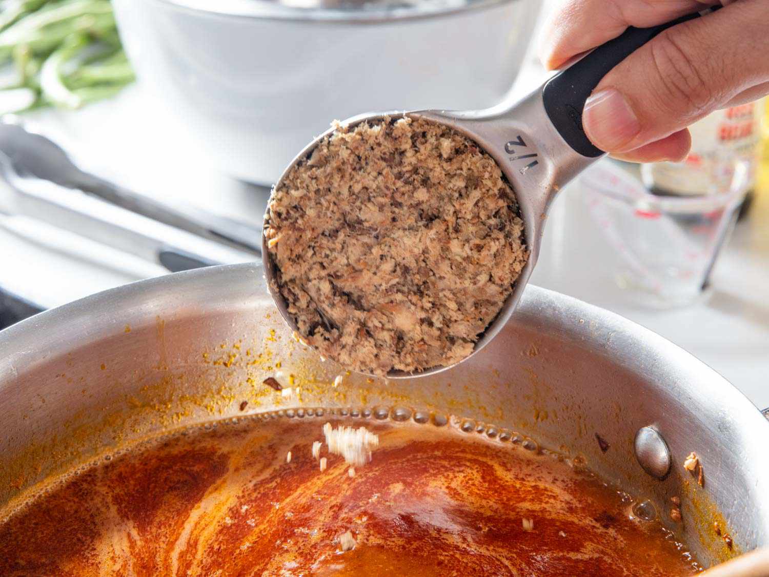 Closeup of flaked smoked fish being added to pan.