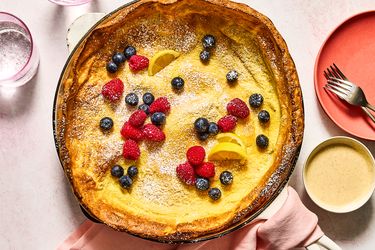 A baked Dutch baby pancake with berries and lemon slices on top
