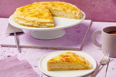 Side view of crepe cake being served from a white porcelain cake stand.