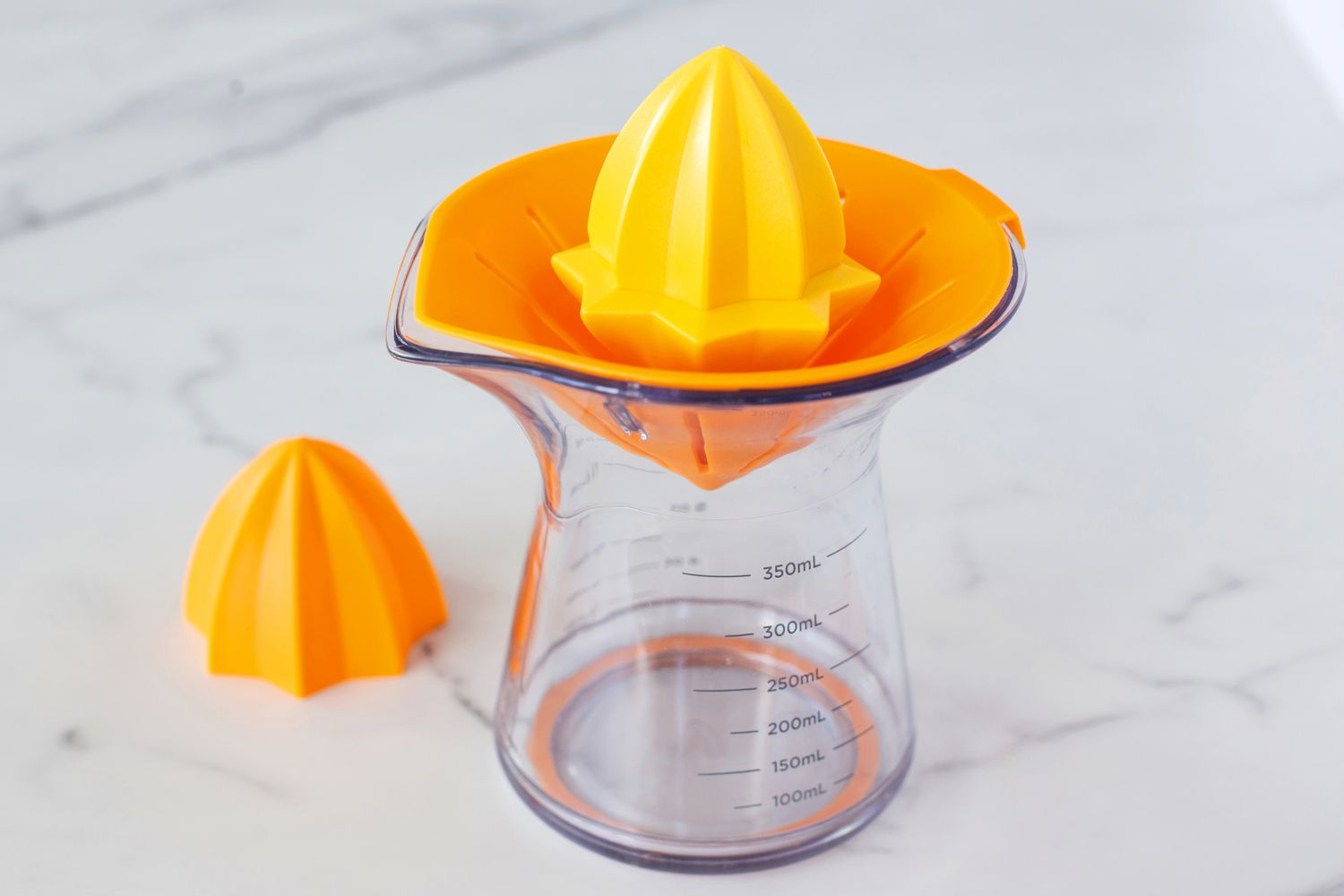 A countertop citrus juicer on a marble countertop.