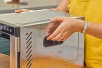 A person holding Magic Mill 7 Tray Pro Food Dehydrator Machine