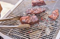 Tongs flipping meat on the PK Grills Original PK300 Grill & Smoker 