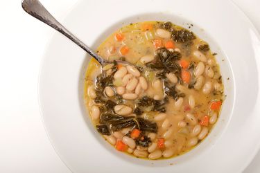 Overhead view of Tuscan white bean soup in a wide, shallow soup bowl.