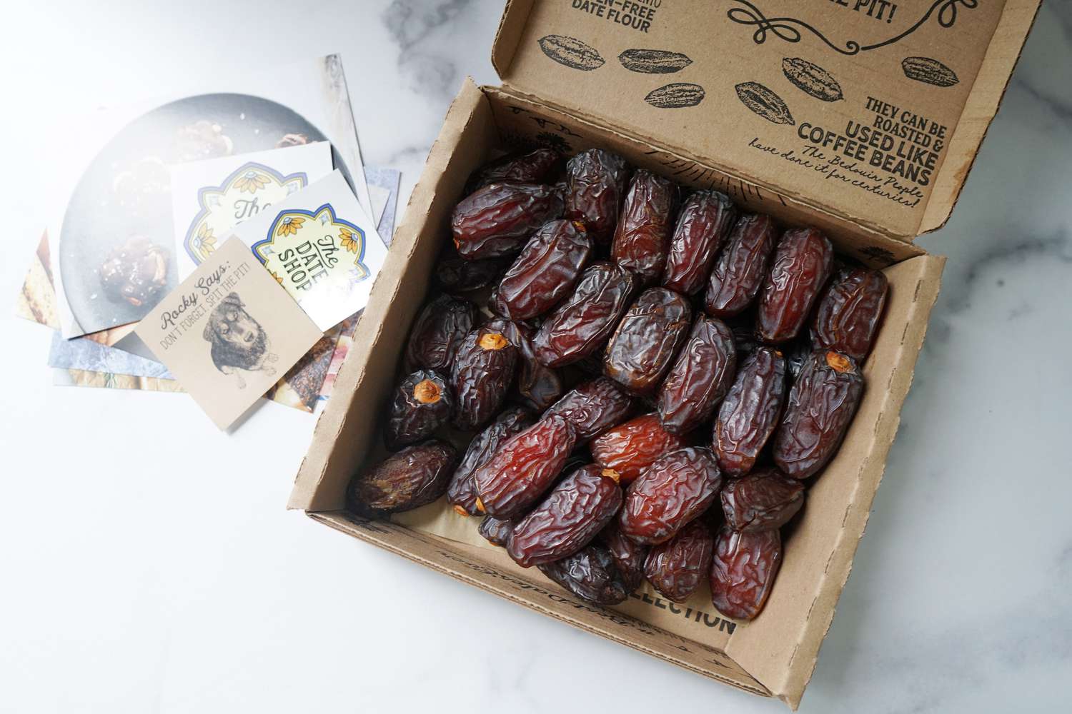 a box of dates with its lid open on a marble surface