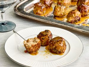Turkey meatballs glazed with maple mustard served on a white plate with a serving tray in the background