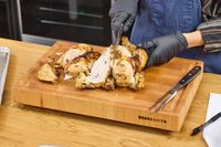 Person carving a roasted chicken on a Boardsmith Maple End-Grain Cutting Board