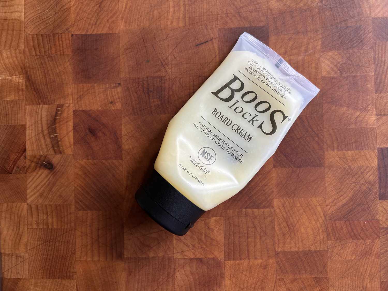 A half-empty tube of Boos Block Board Cream sitting on a just-conditioned wooden cutting board