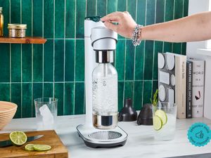 A person carbonating water with a soda maker.
