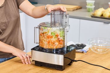 A person chops vegetables in the Cuisinart 14-Cup Food Processor