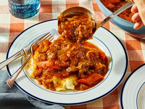 Plate of Swiss steak with mashed potatoes and a serving spoon midaction