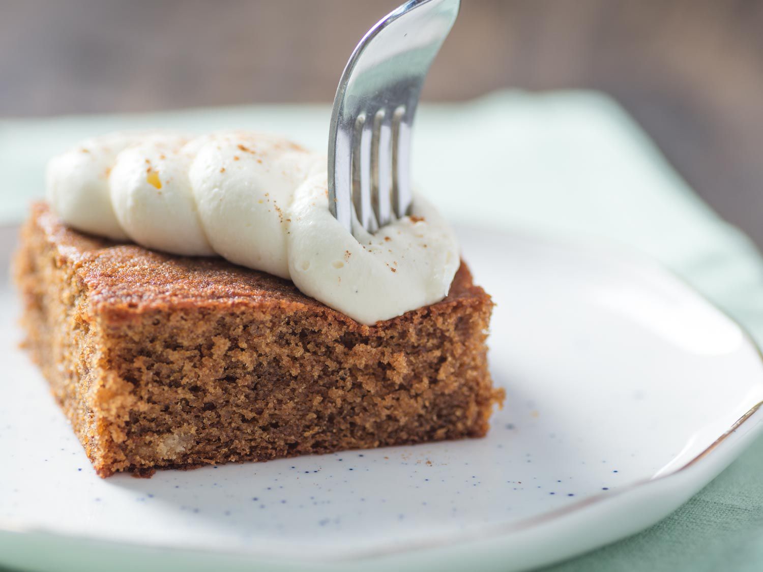 Fork piercing in a square of gingerbread sheet cake with cream cheese frosting