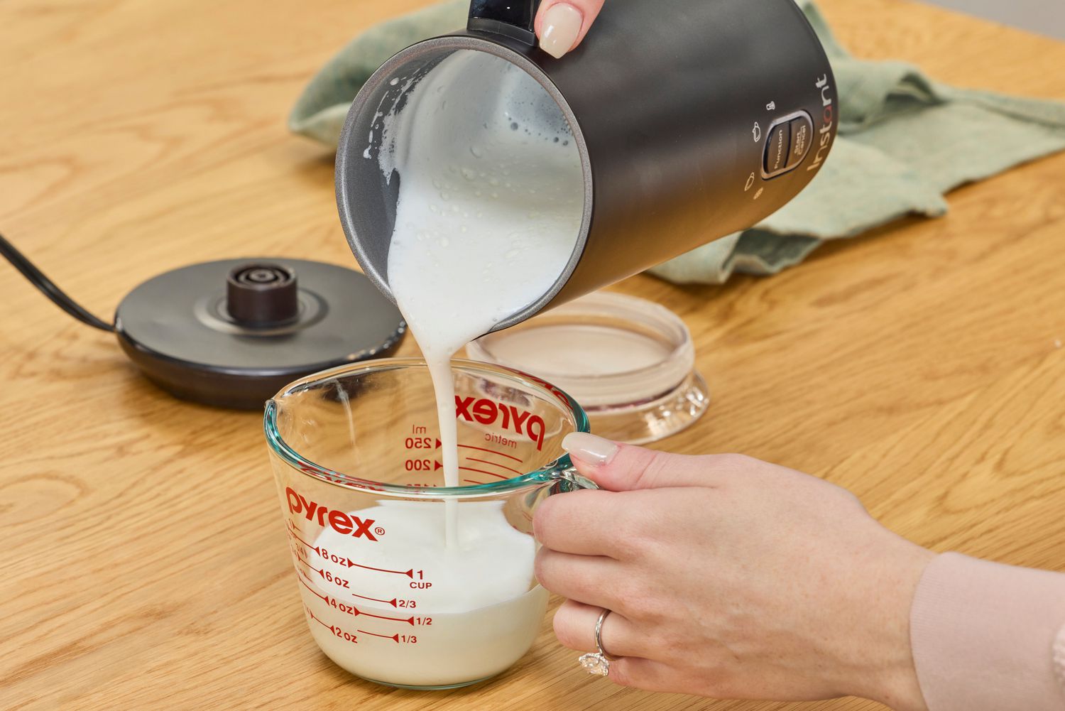 Frothed milk being poured into a liquid measuring cup.