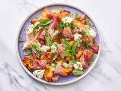 A plate of grilled peach salad with herbs, prosciutto, and cheese