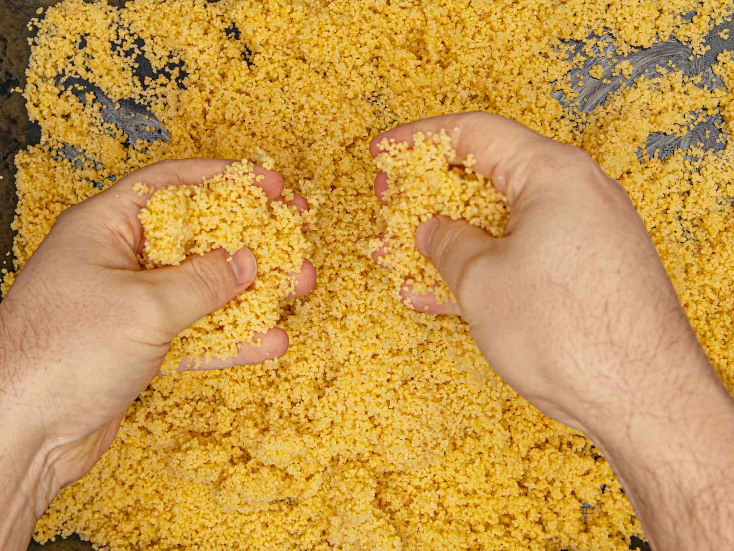 Overhead view of using hands to fluff couscous
