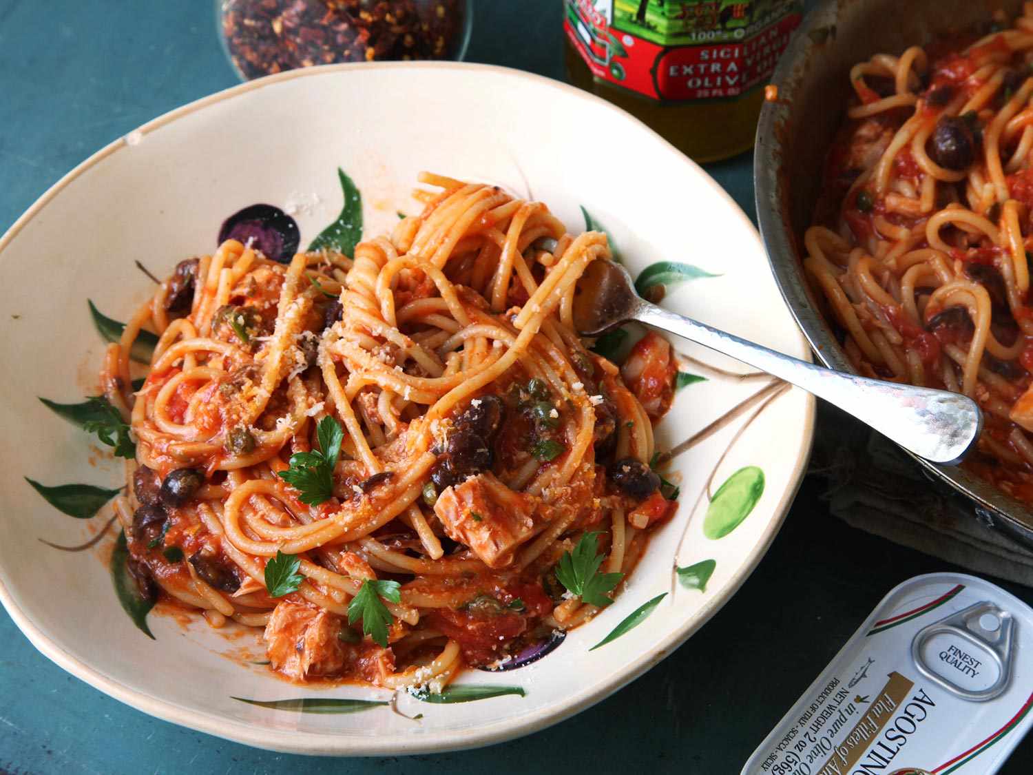Pasta puttanesca, made with spaghetti, in a bowl with a fork.
