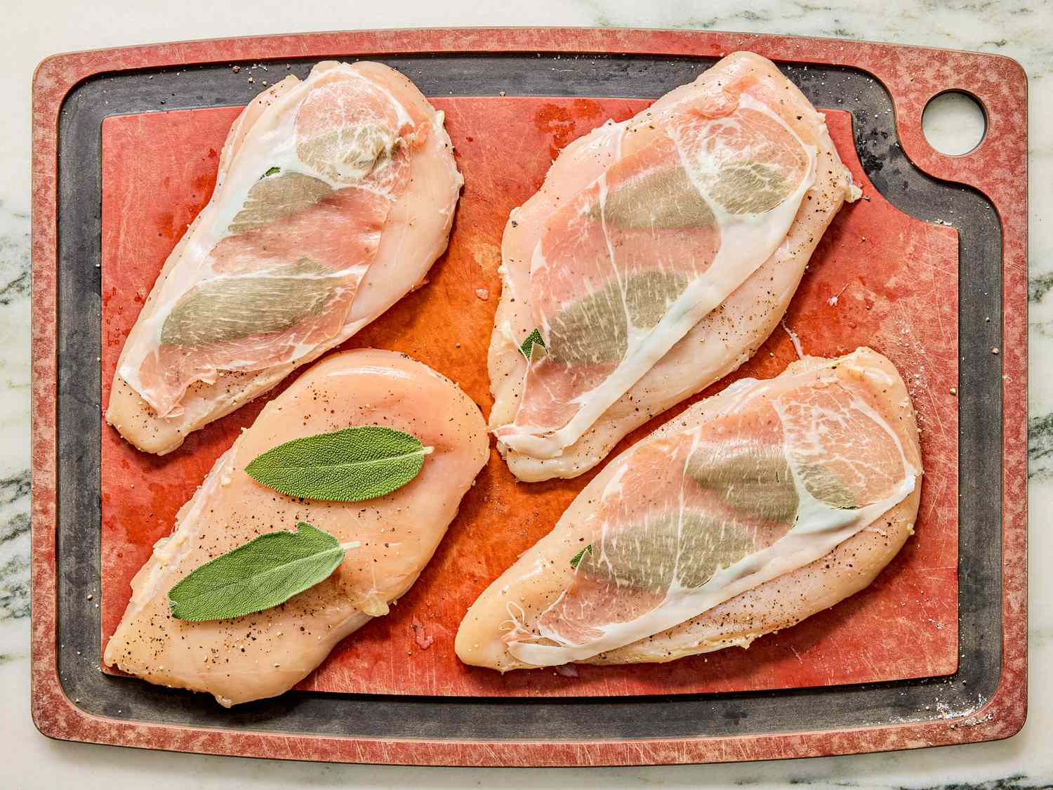 Chicken breasts prepared with sage and thinly sliced prosciutto on a cutting board