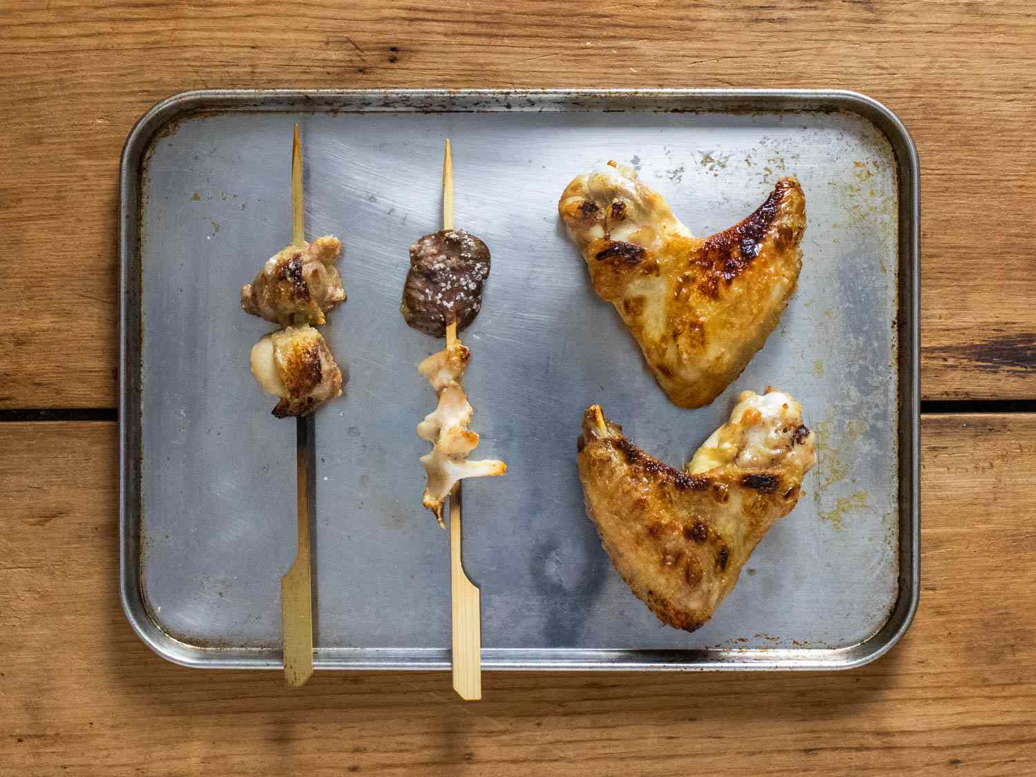 Chicken oysters, heart, chest cartilage, and wings broiled on a rimmed baking sheet