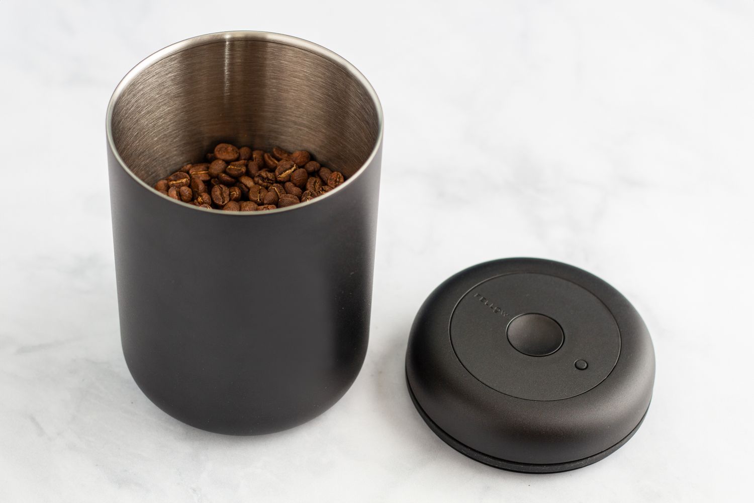 The Fellow Atmos Vacuum Coffee Canister open on a marbled surface