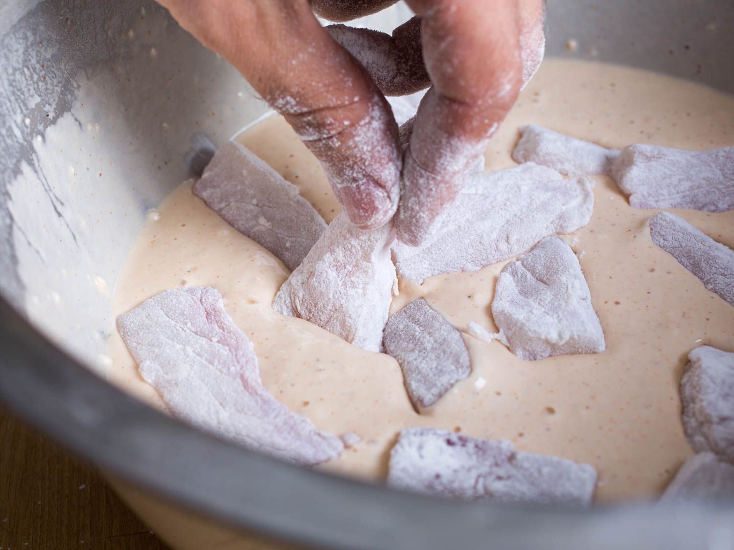 Dipping flour-coated fish pieces into batter