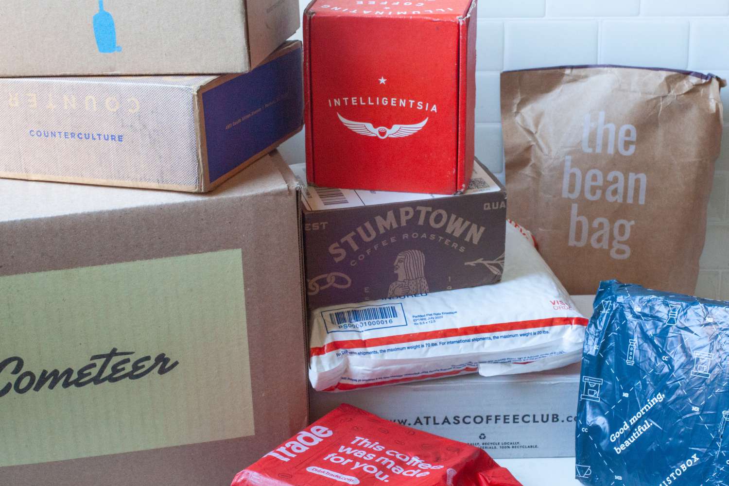 Numerous boxes from coffee subscriptions on a marble countertop.