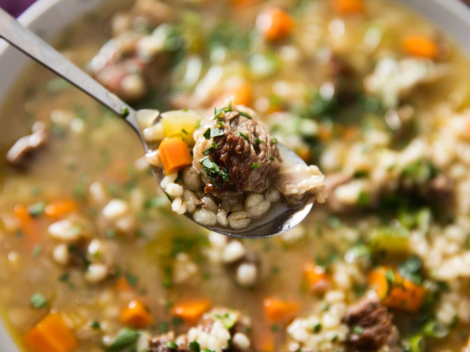 A spoonful of beef and barley soup.
