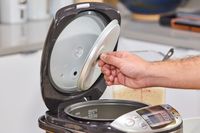 A person removes a lid cover on the Zojirushi NS-TSC10 Miacom Rice Cooker and Warmer