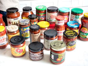 A collection of various salsa jars displayed on a white counter, showcasing different brands and types of salsas