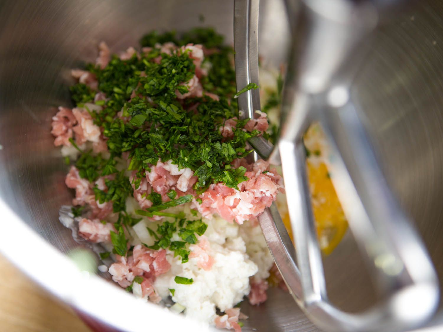 Flavoring ingredients, eggs, and gelled stock in stand mixer bowl for meatballs.