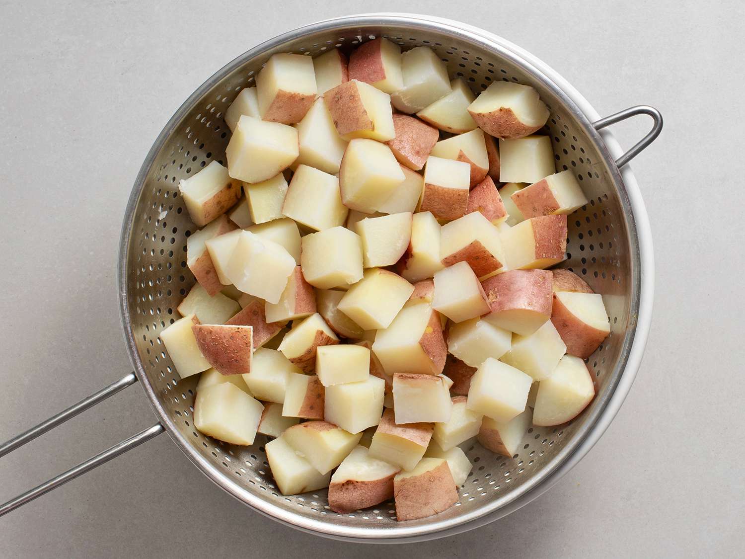 Cooked and drained potatoes in a metal colander.
