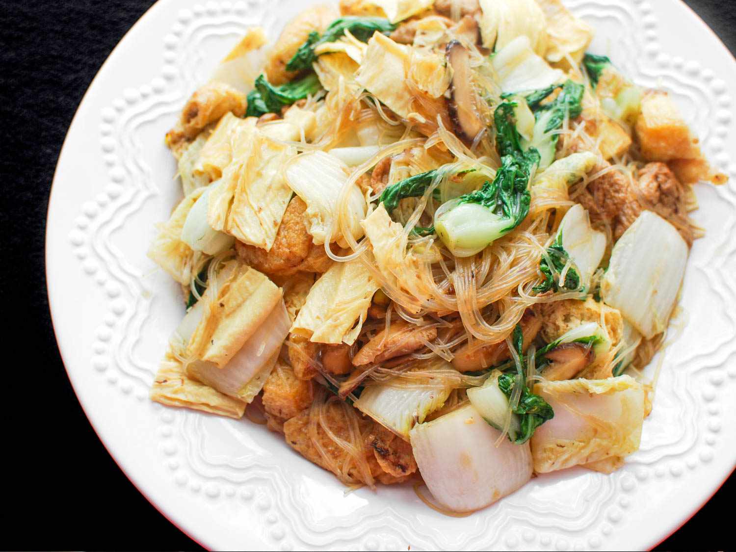 Closeup of Buddha's delight stir-fry, served on a white plate with raised decoration on the rim.