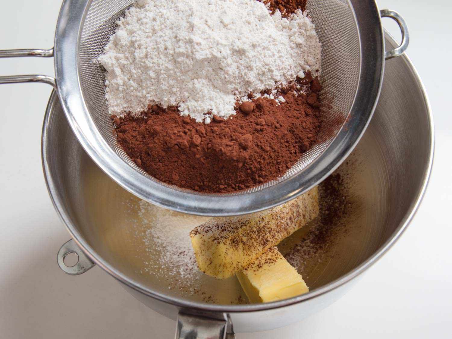 Sifting cocoa and powdered sugar over butter.